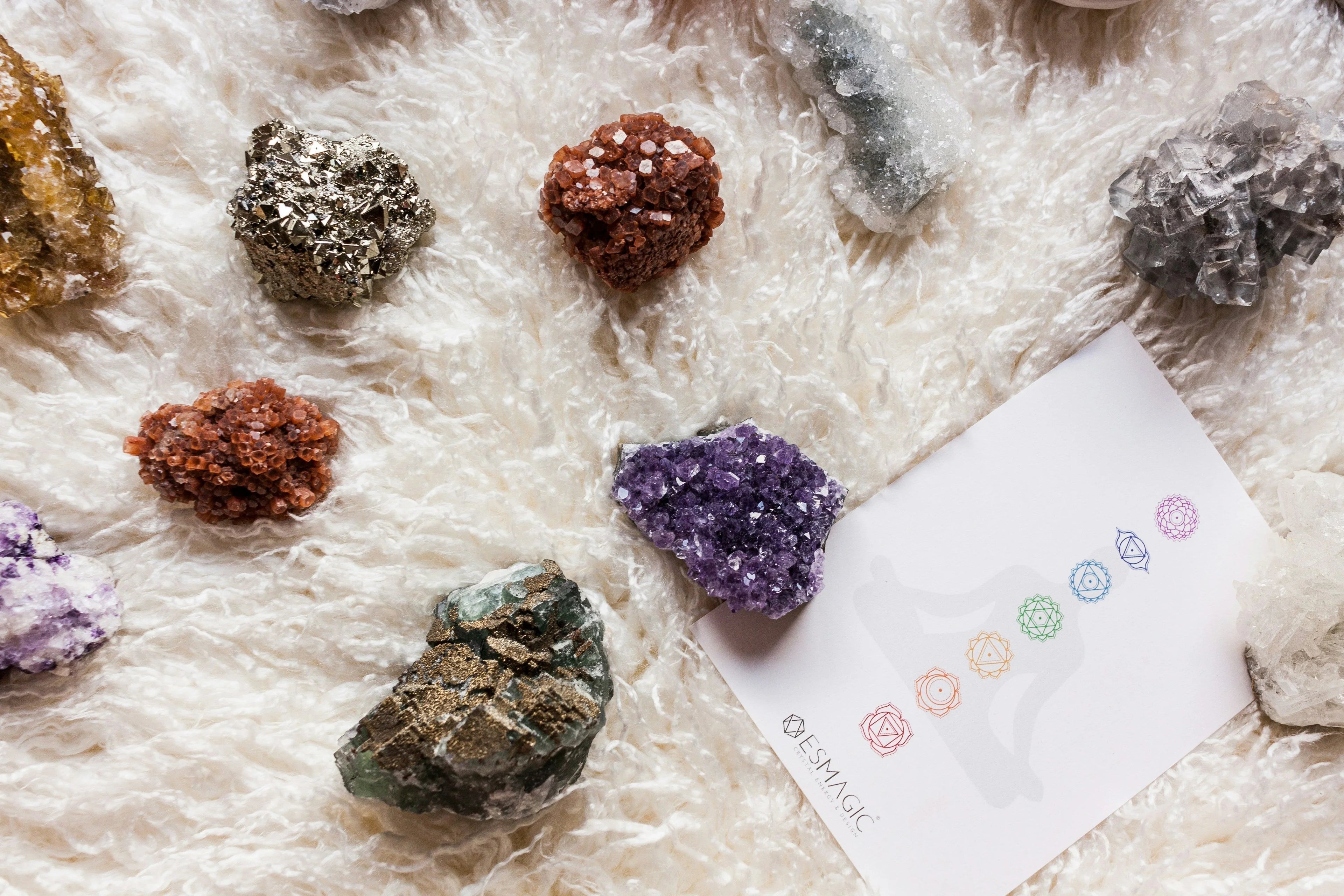 An assortment of natural crystals aligned with chakra symbols, representing balance and energy healing.