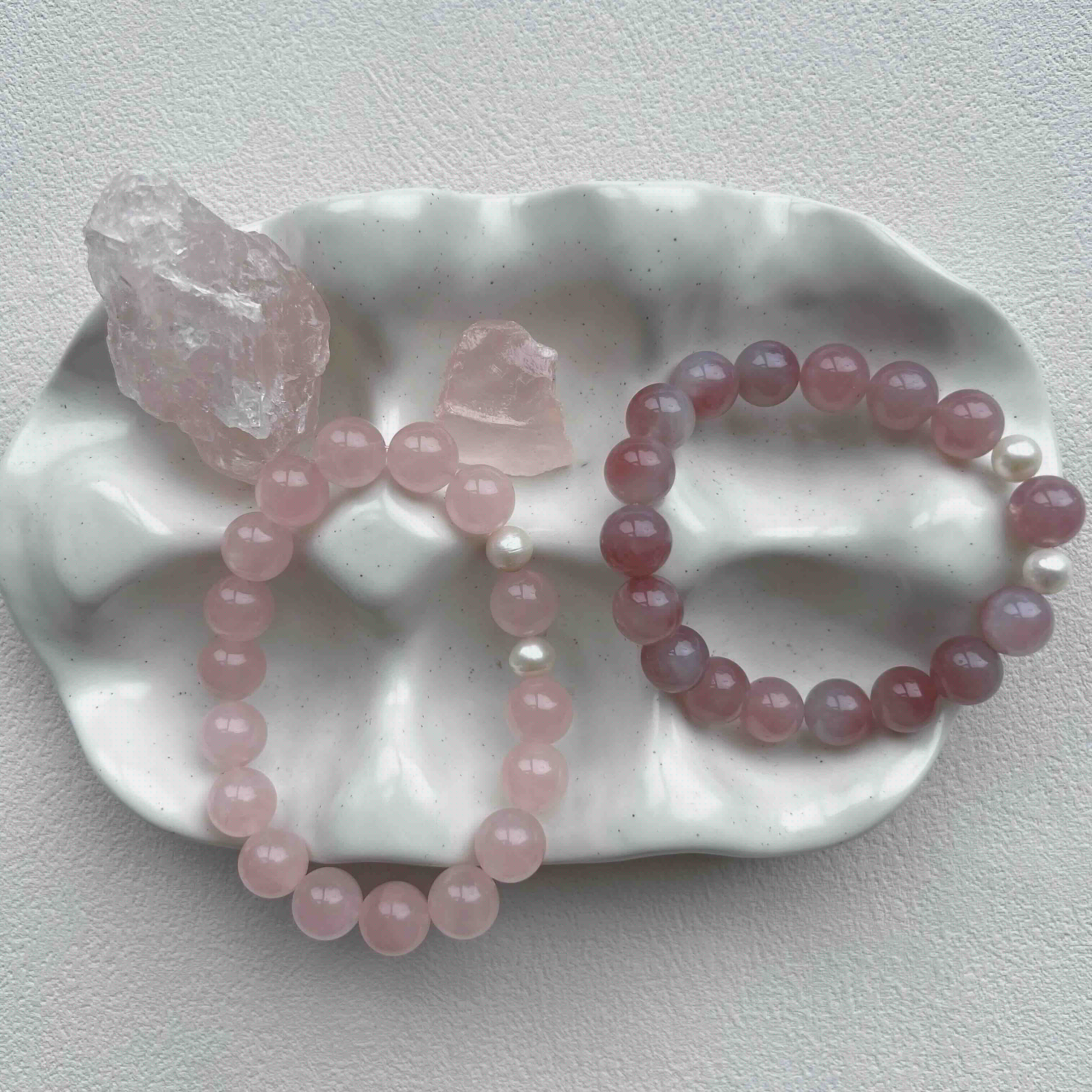 Rose Quartz crystal bracelets with freshwater pearls displayed beside raw Rose Quartz stones on a ceramic dish – pink gemstone for love, compassion, and heart chakra healing
