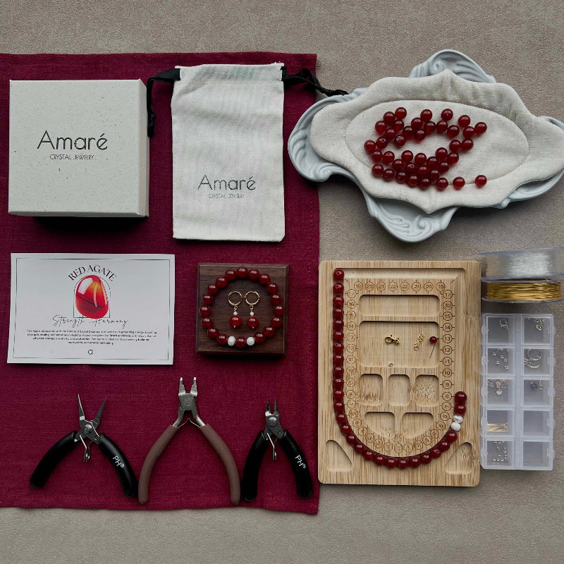 Jewelry-making kit with beads, tools, and branded materials on a gray surface