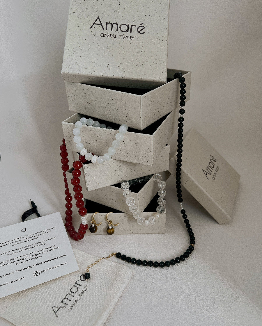 Jewelry set with beads and earrings displayed in front of an 'Amaré' jewelry box.