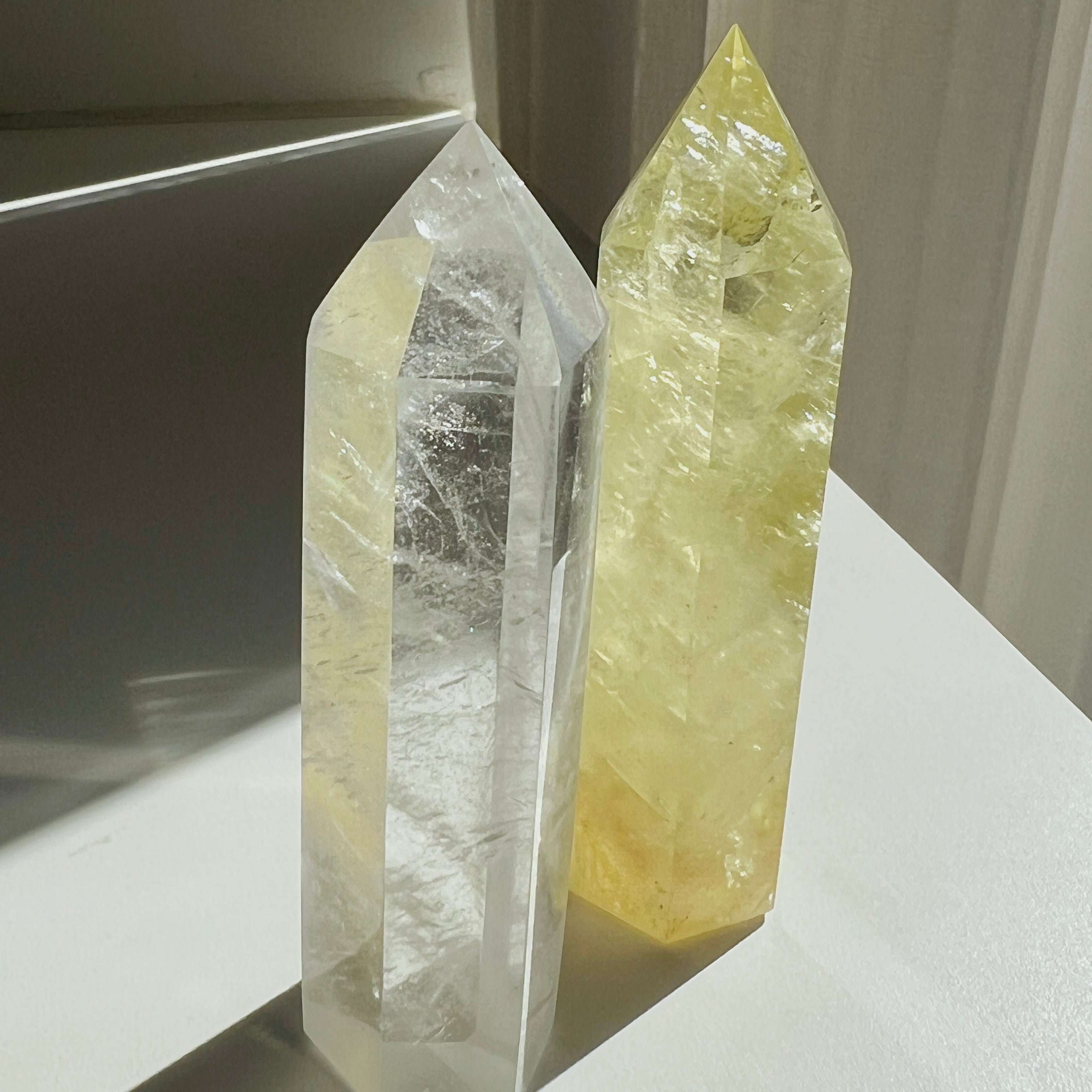 Two crystal towers, one clear and one yellow, on a white surface.