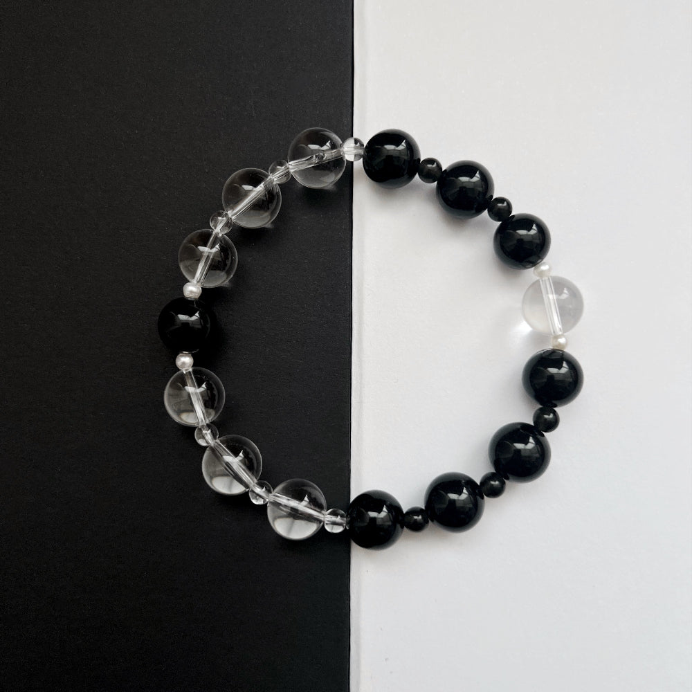 Amaré Yinyang necklace featuring a 10mm black obsidian stone and a 12mm high-grade clear quartz bead with freshwater pearl accents on an 18k gold-plated chain, void and form collection.