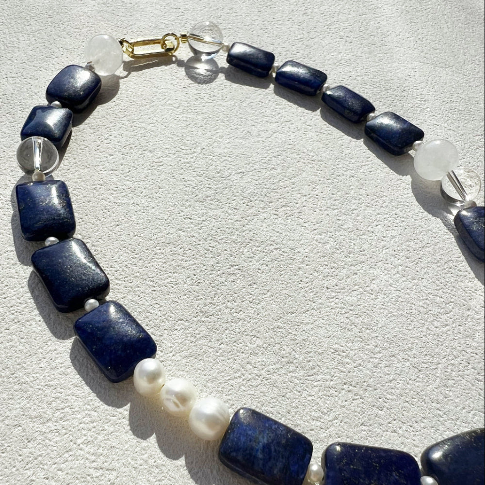 Macro detail of the Amaré Qinghua necklace from the vold & form collection, highlighting the natural textures of high-grade white jade and cobalt lapis lazuli gemstones.