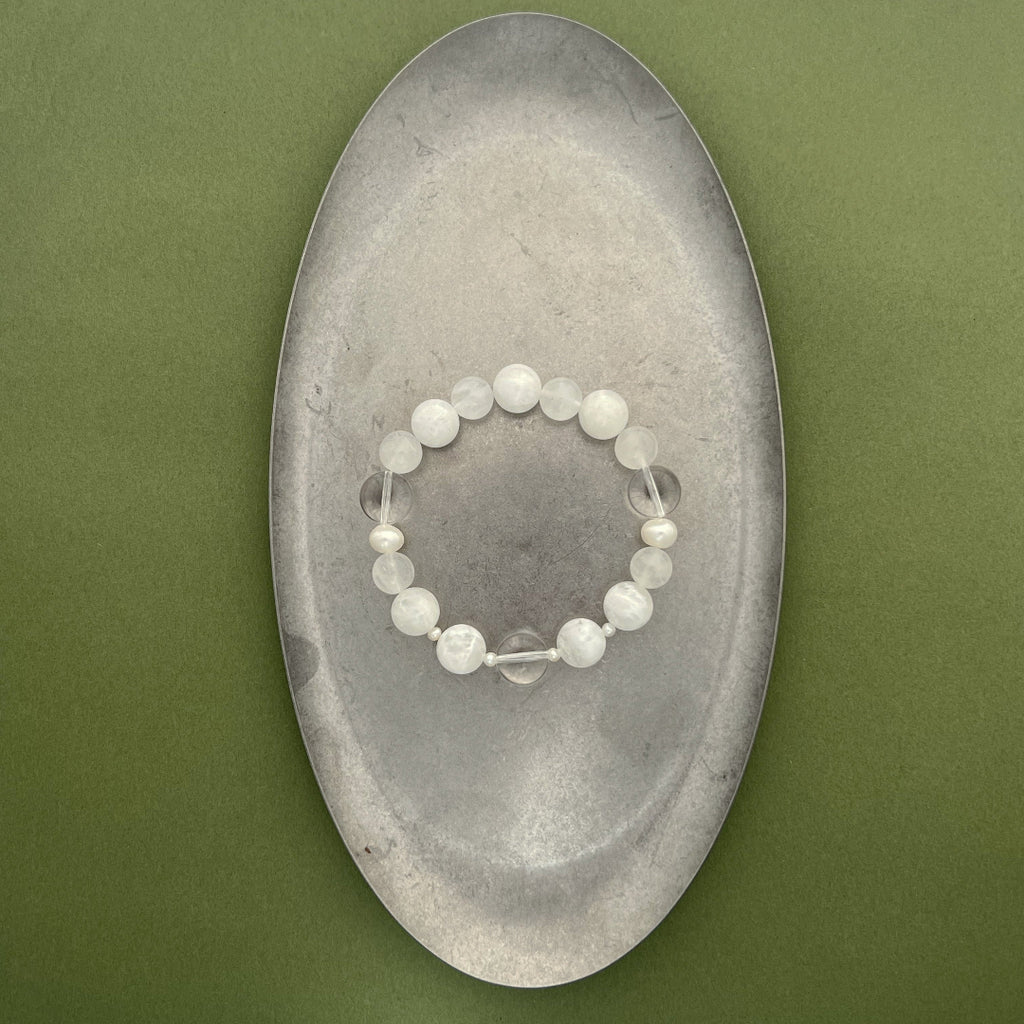 A full view of the Qi stretch bracelet from the void & form collection, highlighting the elegant balance of 12mm phantom quartz and organic freshwater pearls on a clean background.