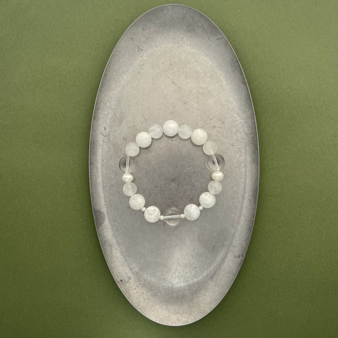 A full view of the Qi stretch bracelet from the void & form collection, highlighting the elegant balance of 12mm phantom quartz and organic freshwater pearls on a clean background.