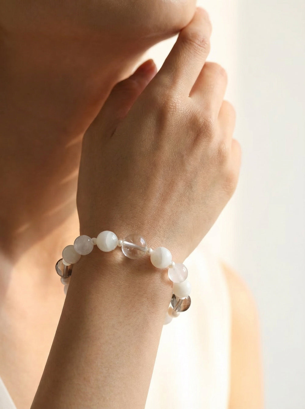 A model wearing the minimalist Qi stretch bracelet on the wrist, demonstrating the elegant scale of the 12mm phantom quartz and white jade gemstones.