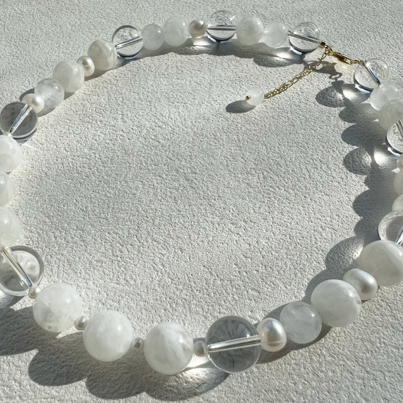 Macro shot of the Qi necklace components, contrasting the clarity of 12mm clear quartz with the soft glow of 3mm accent pearls and white jade.