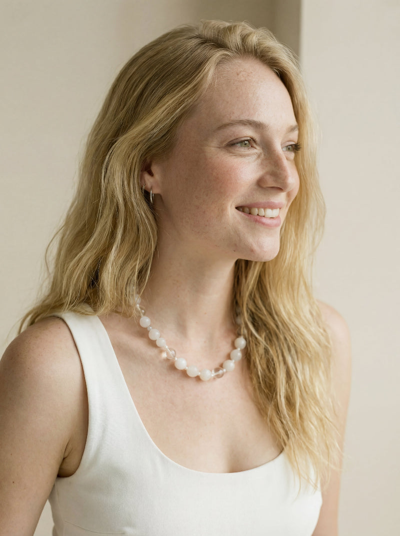 Lifestyle image of the Qi necklace as a wearable talisman of vitality, highlighting its ethereal white aesthetic and elegant drape against minimalist attire.