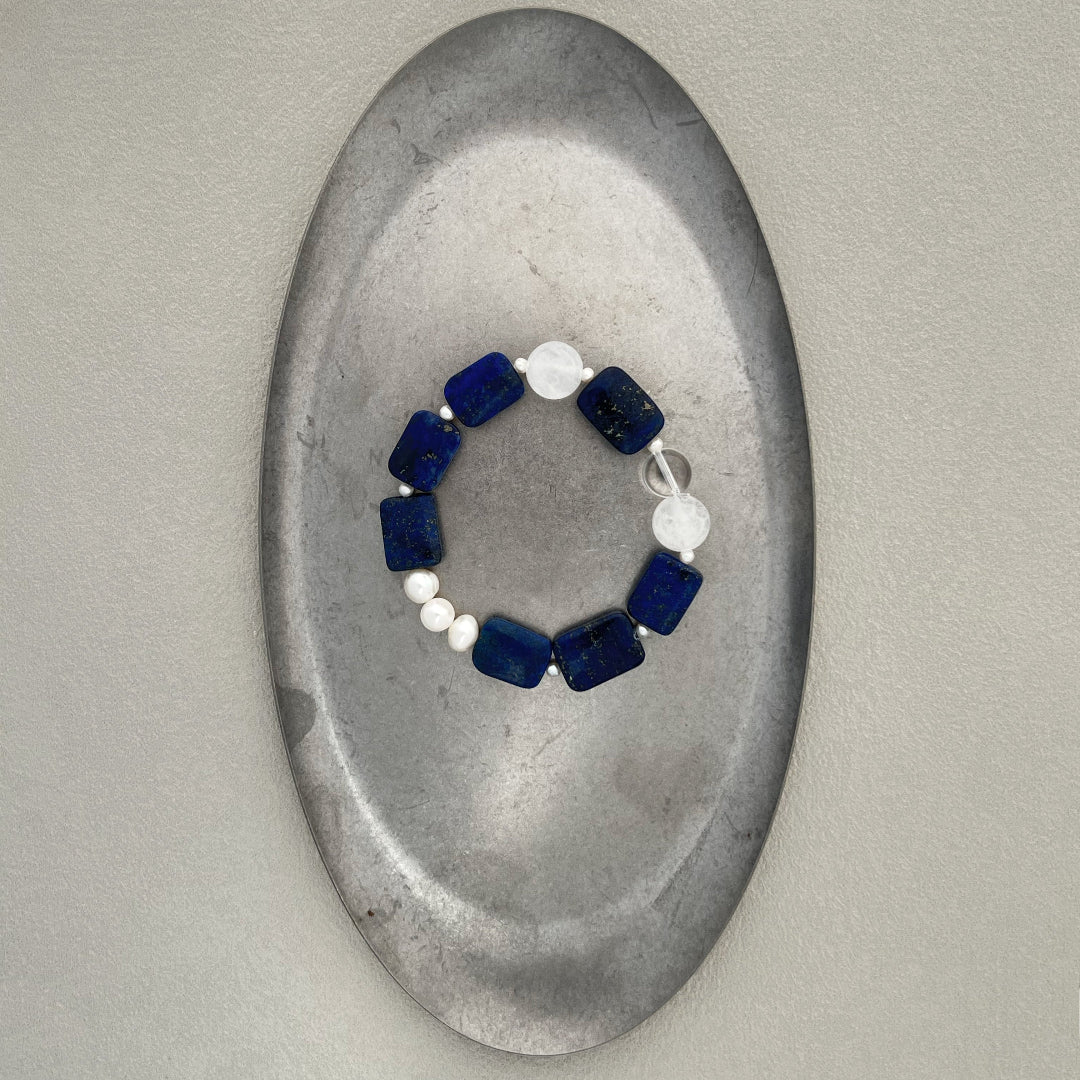 Amaré Qinghua stretch bracelet featuring a misty white jade bead, deep blue lapis lazuli, and a lustrous freshwater pearl on a durable elastic cord, void and form collection.