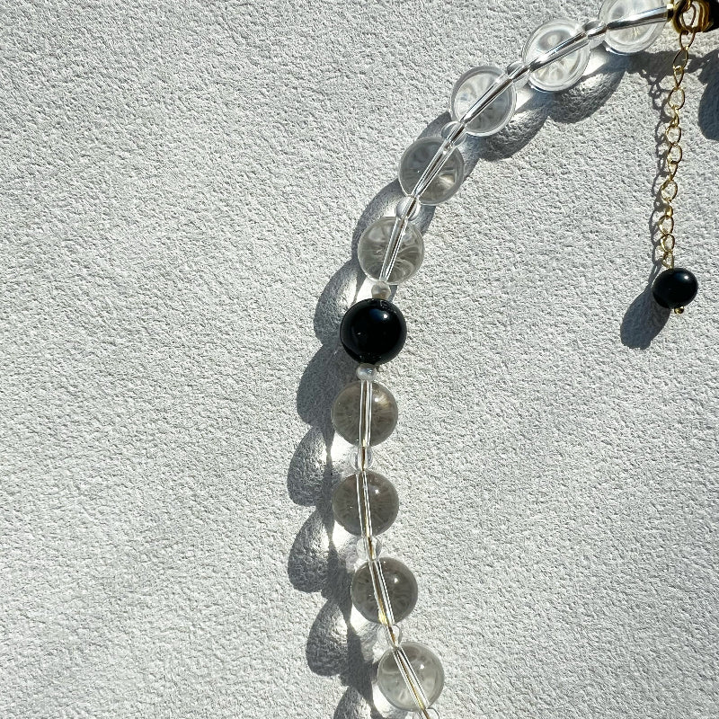 Close-up of the 10mm high-grade clear quartz bead, showcasing its crystal clarity and ability to capture light within the void & form design.