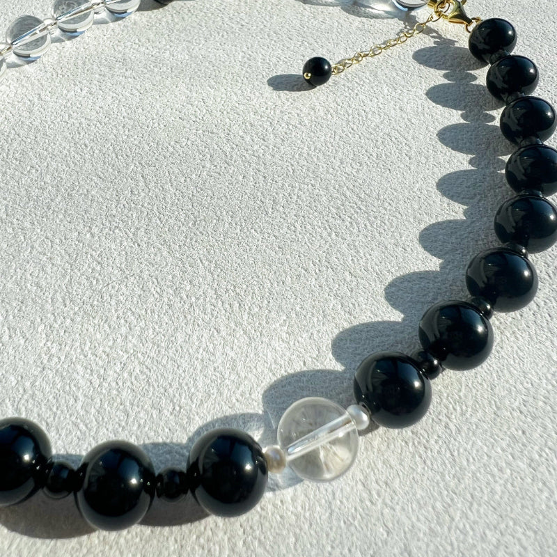 Macro detail of the 10mm natural black obsidian stone on the Yinyang necklace, representing grounding energy and protective shadow.