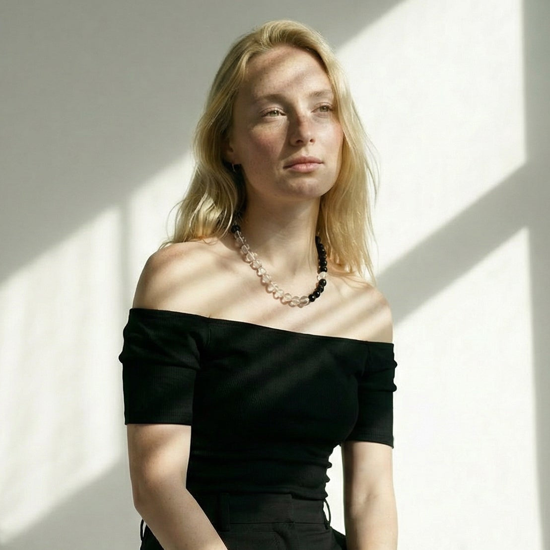 A model wearing the minimalist Yinyang necklace on the collarbone, demonstrating the scale of the 10mm clear quartz and obsidian stones against the skin.