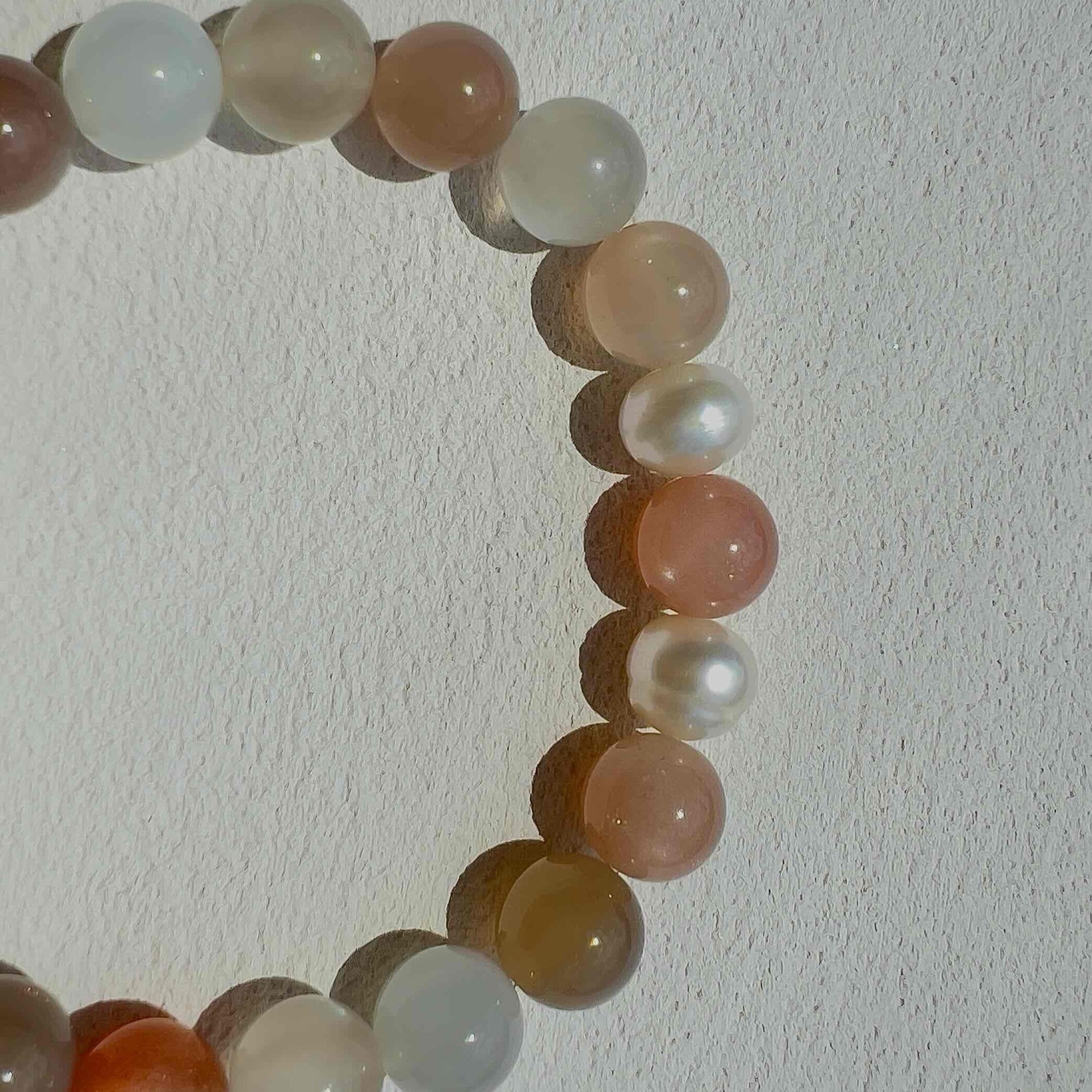 Close-up of Aura Moonstone Bracelet featuring a blend of white, grey, and peach moonstone beads with freshwater pearls, highlighting its calming energy and elegant handcrafted detail.