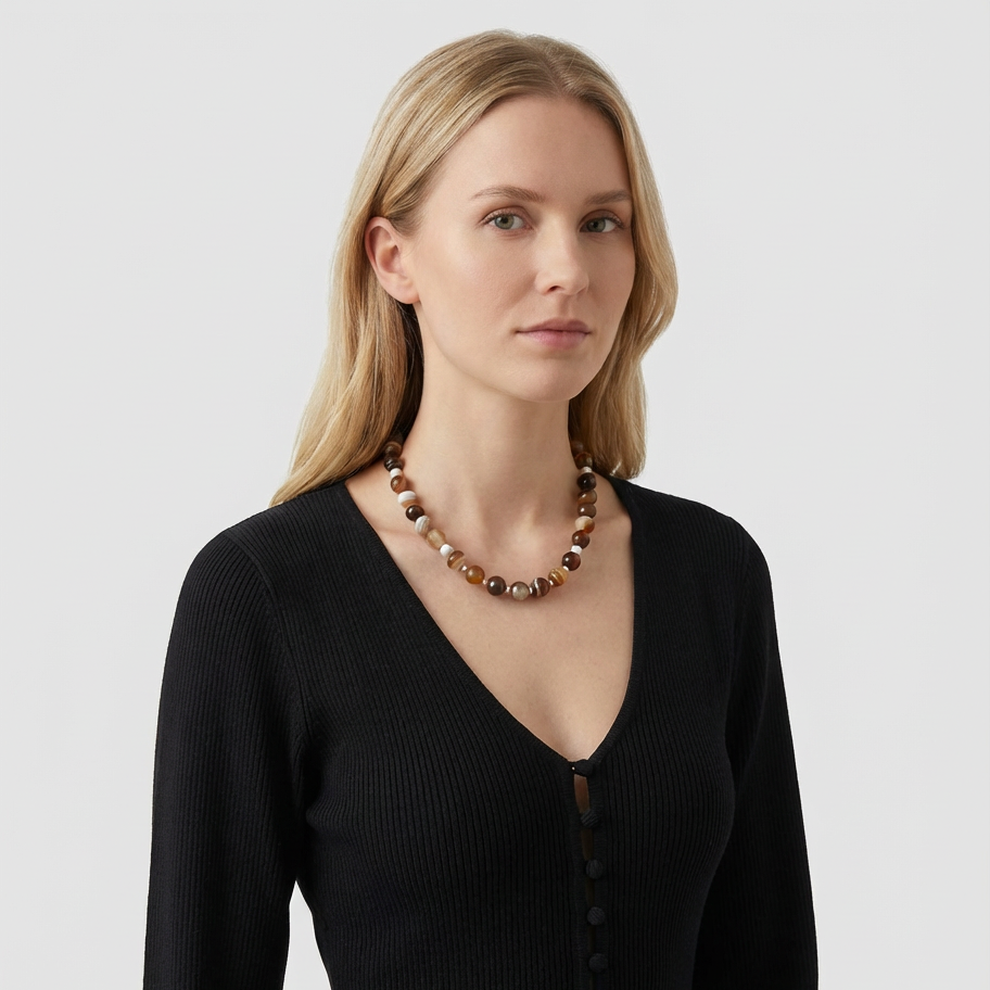 Woman wearing Amarè latte onyx necklace with a neutral background